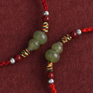 Close-up detail of dual green jade gourds with colorful woven knots and red silver beads