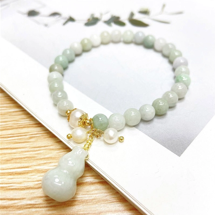 Gradient green jade gourd bracelet with pearl details on wooden background