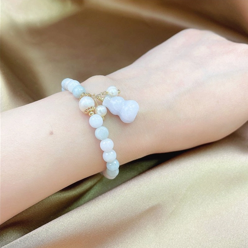 Pale blue jade gourd prosperity bracelet worn on wrist close-up