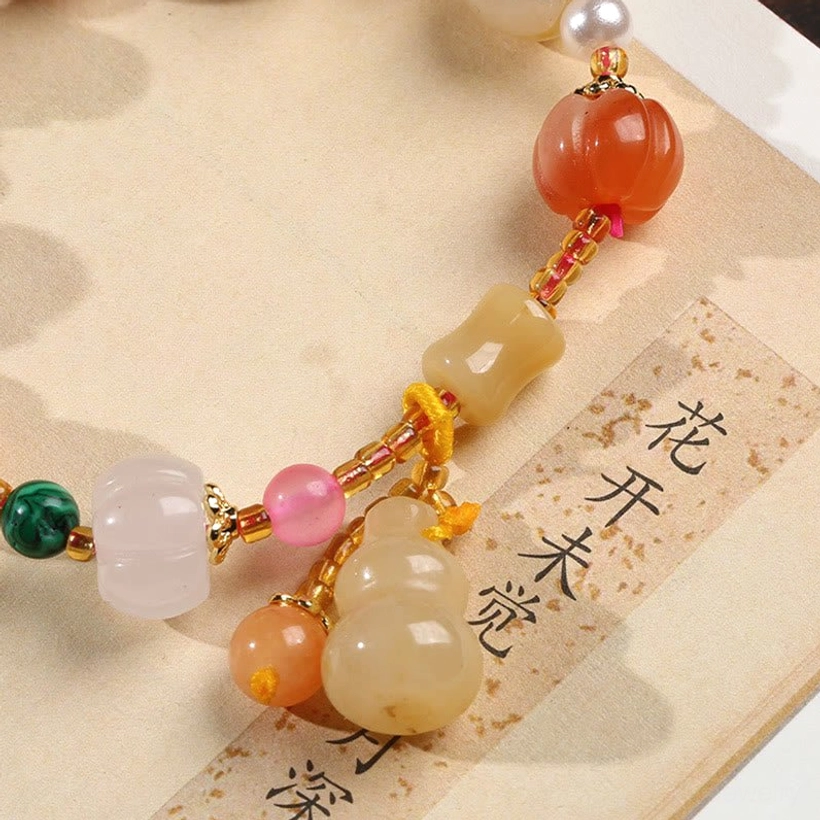 Close-up jade bracelet pumpkin beads gourd pendant colorful stone beads on calligraphy paper
