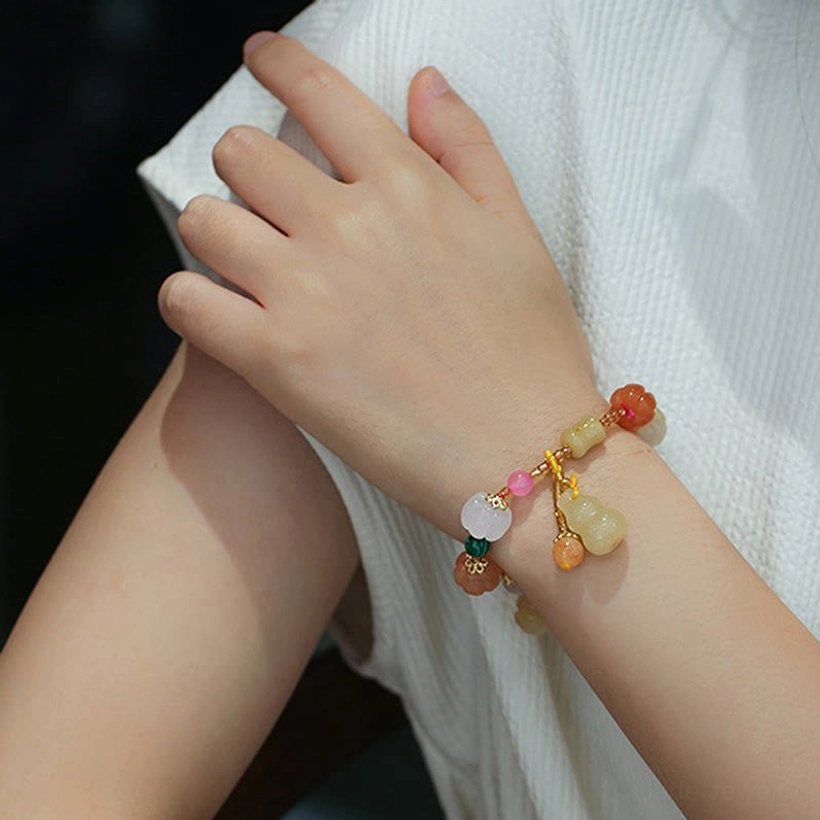Jade charm bracelet on hands showing multi-color stone beads gourd pendant gold hardware
