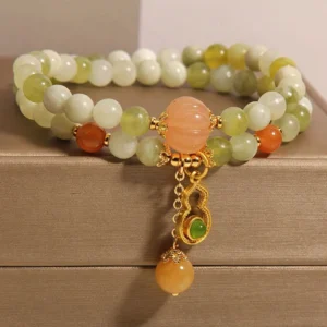 Close-up of jade beads and amber gourd charm with gold accent on double wrap lucky bracelet