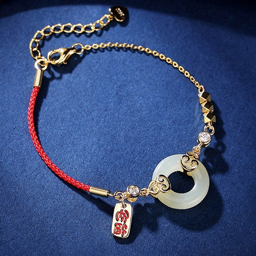 Flat lay of complete jade peace buckle bracelet set showing gold-toned hardware, fortune charm pendant, and red protective cord