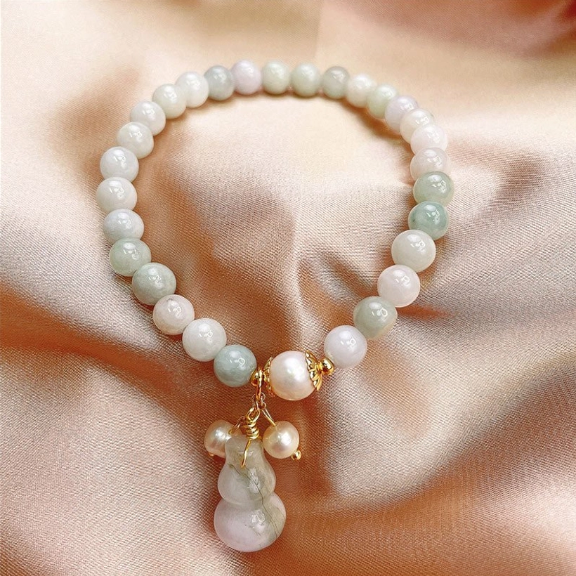 Jade gourd prosperity bracelet with gold hardware and freshwater pearls on champagne satin fabric
