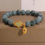 Natural blue-grey jade gourd charm bracelet with gold-toned hardware, displayed on luxury brown jewelry gift box