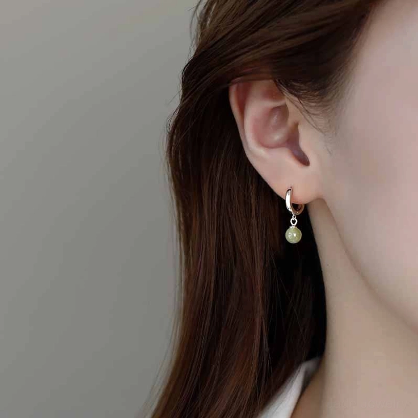 Delicate jade bead drop earrings worn from back view with brown hair, dangling light green jade charm on silver hoop
