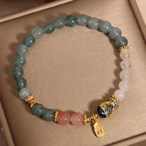 Handmade jade prosperity bracelet overhead flat lay showing mixed green pink white jade beads with koi charm detail