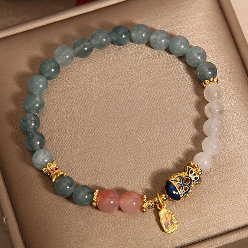 Handmade jade prosperity bracelet overhead flat lay showing mixed green pink white jade beads with koi charm detail
