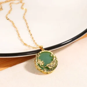 Natural jade koi fish pendant necklace on twisted gold chain displayed on wooden surface with ceramic plate