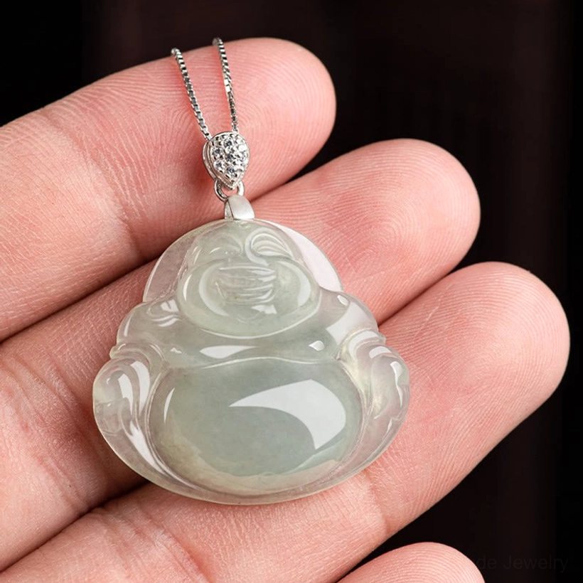 Laughing Buddha jade pendant held in hands showing light green translucent jade with decorative silver chain bail