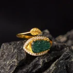 Natural jade leaf gold adjustable ring - top-down front view showcasing carved green jade leaf with gold-plated copper band and sparkling crystal accents on dark stone background
