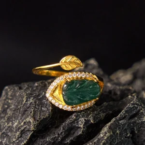 Natural jade leaf gold adjustable ring - top-down front view showcasing carved green jade leaf with gold-plated copper band and sparkling crystal accents on dark stone background