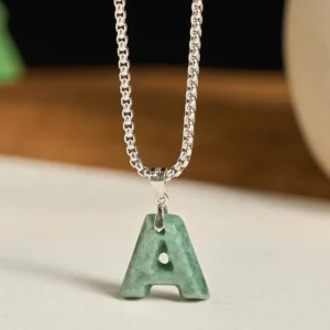 Close-up front view of polished green jade letter A pendant with silver titanium steel curb chain