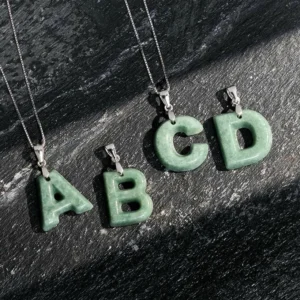 Collection of jade letter pendants A B C D with 925 sterling silver chains on dark slate display
