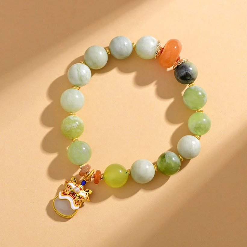 Overhead view of jade dancing lion charm bracelet with circular beaded strand and enamel lion pendant on warm tabletop