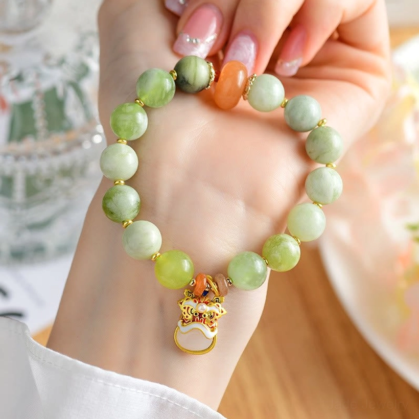 Woman wearing jade dancing lion charm bracelet on wrist with white shirt cuff and wooden table background