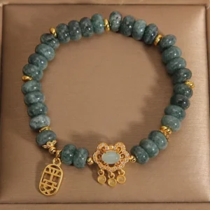 Top-down view of jade beaded bracelet with floral jade-set centerpiece and gold metal accents