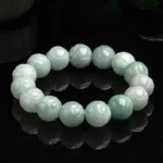 Natural jade lotus carving bracelet with gradient light green and white beads, carved lotus details, overhead flat lay on black studio background