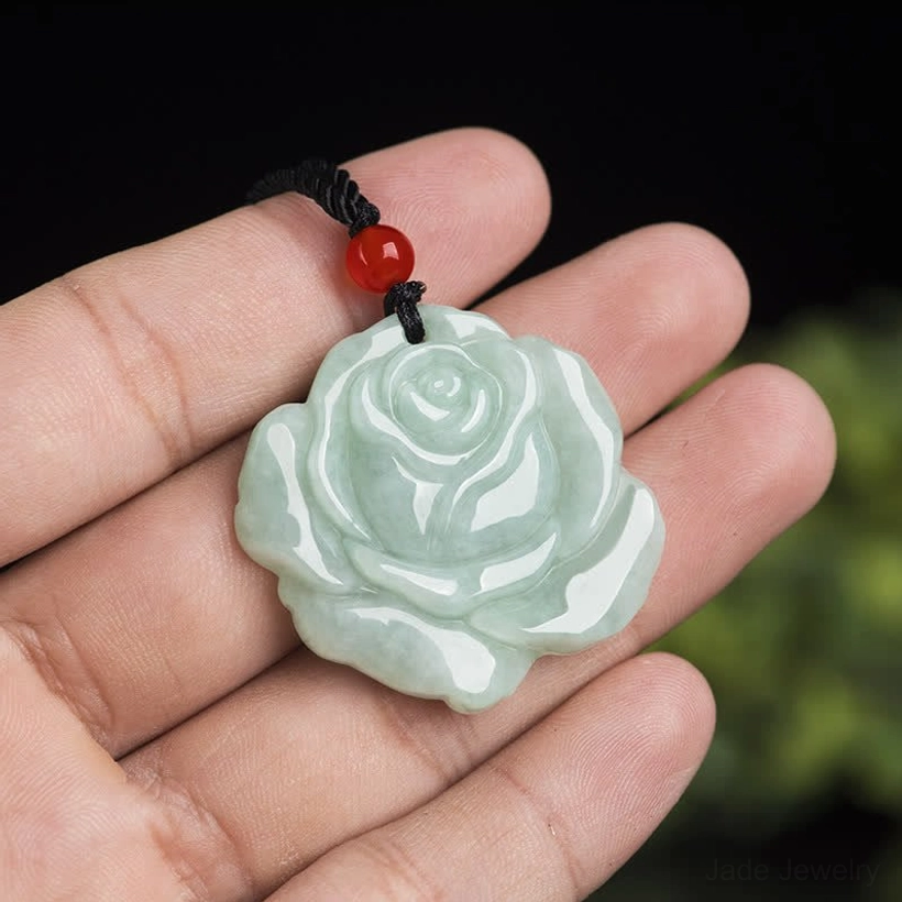 Hand-held jade lotus rose pendant in palm demonstrating compact size and glossy polished jade texture