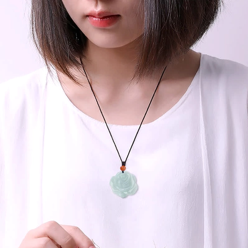 Woman wearing jade lotus rose pendant necklace at collarbone, styled with white casual outfit for everyday elegance