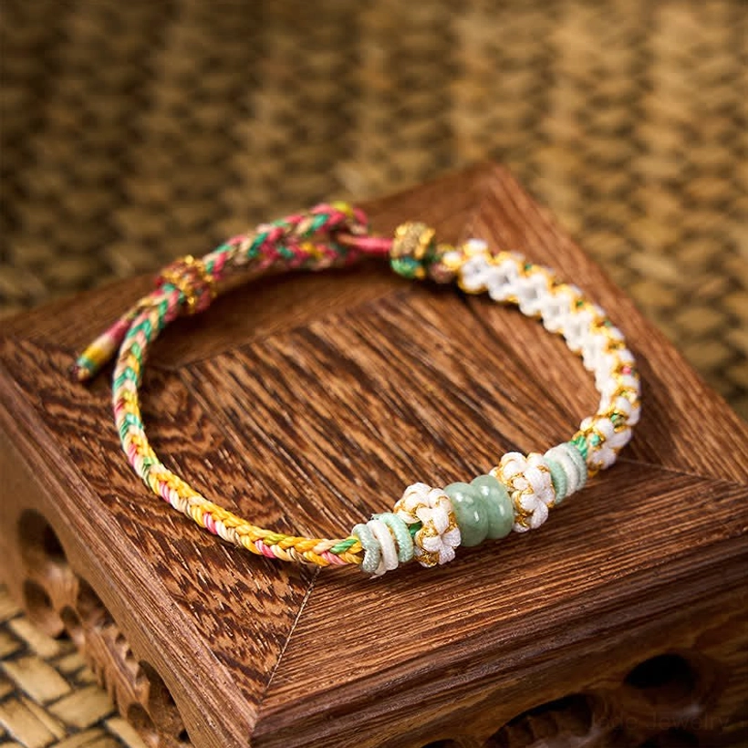 Jade luck bracelet with red woven cord and flower knot accent