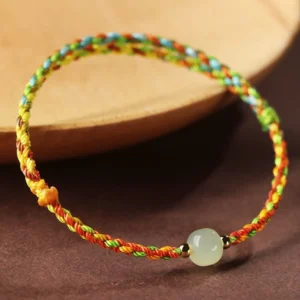 Handcrafted jade bead bracelet on wooden surface showing woven rope detail and polished jade stone