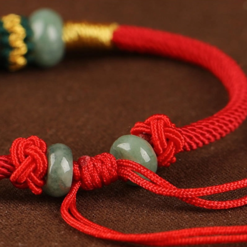 Jade red string lucky charm bracelet displaying full length and adjustable knot mechanism from flat lay view