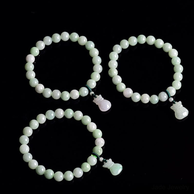 Set of jade charm bracelets displayed in top-down flat lay on black background, multiple bead sizes and various jade pendants shown