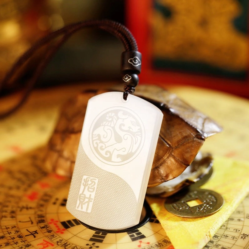 White jade pendant necklace in side oblique view paired with vintage copper coins and decorative beaded cord on Feng Shui compass