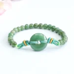 Green jade peace buckle prosperity bracelet with 6mm beads and braided knot accents on white background