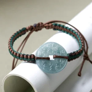Natural jade peace buckle bracelet with adjustable woven cord, displayed in oblique top-down view