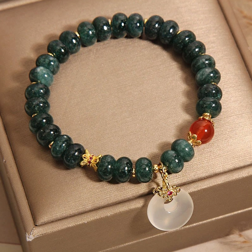 Top-down flat lay of complete jade peace buckle bracelet in jewelry box, showing full circular layout with red agate and gold spacers