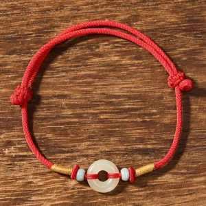 Top-down view of peace buckle jade bracelet showing smooth polished jade pendant and adjustable red cord