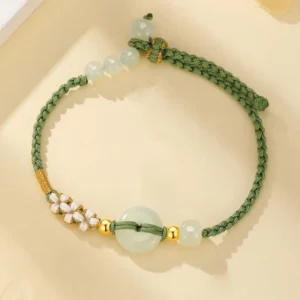 Top-down flat lay view of jade peace buckle braided bracelet showing green woven cord, round jade beads, central peace buckle detail, and adjustable knot closure