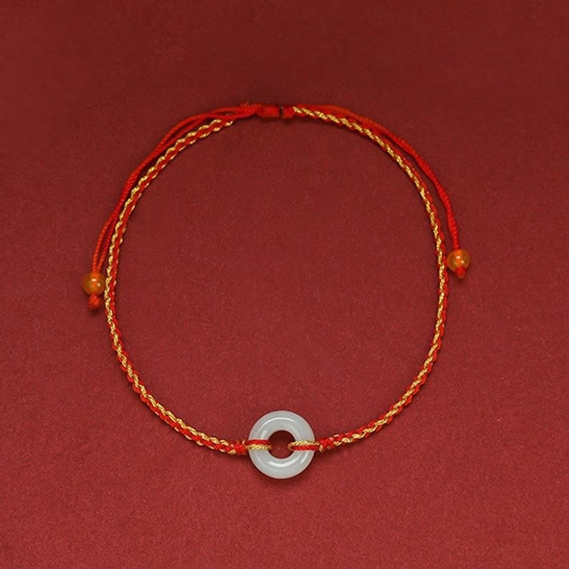 Complete jade peace buckle bracelet loop centered on dark red background, showing full circular design and braided detail