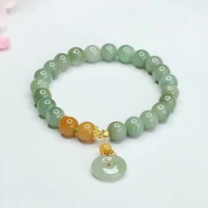 Green jade peace buckle bracelet with orange accent beads and gold hardware, top-down view with pink floral styling