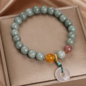 overhead view of green jade beaded bracelet with peace buckle charm on brown leather jewelry tray