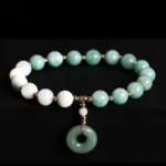 Jade peace buckle charm bracelet overhead flat lay view with mixed green jade and white round beads and gold spacers on black studio background
