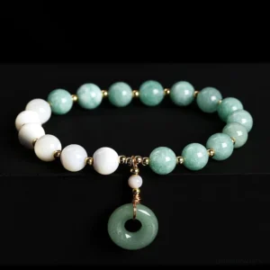 Jade peace buckle charm bracelet overhead flat lay view with mixed green jade and white round beads and gold spacers on black studio background