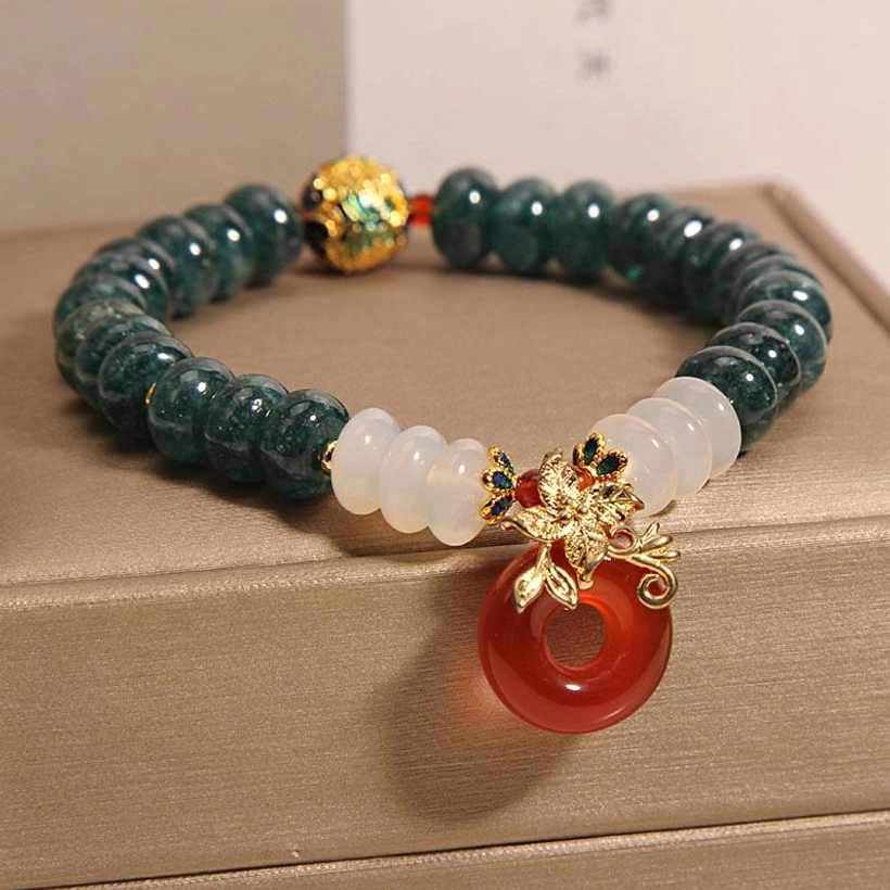 Red agate peace buckle pendant close-up detail with gold enamel spacer bead on beaded jade bracelet