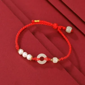 Single red string jade peace buckle bracelet with white pearls and gold-plated silver beads flat lay