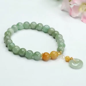 Jade peace buckle bracelet side perspective showing matte green beads, orange spacer beads, and gold-tone peace buckle charm