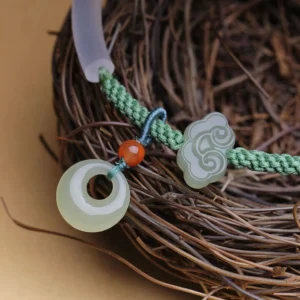 Close-up side view of jade peace buckle bracelet on natural twig nest, detailed view of braided cord and jade decorations