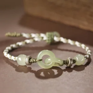Close-up side angle of natural jade peace buckle bracelet featuring two-tone woven rope and polished jade buckles against brown background
