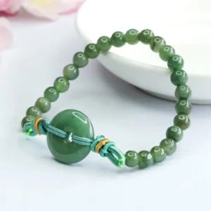 Side profile view of green jade peace buckle bracelet curved on ceramic plate