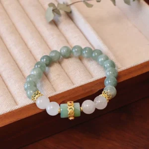 Single layer jade peace buckle bracelet with 8mm green and white jade beads and gold metal spacers on wooden jewelry display mat