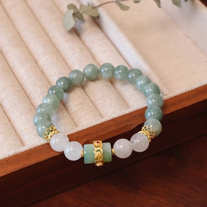 Single layer jade peace buckle bracelet with 8mm green and white jade beads and gold metal spacers on wooden jewelry display mat