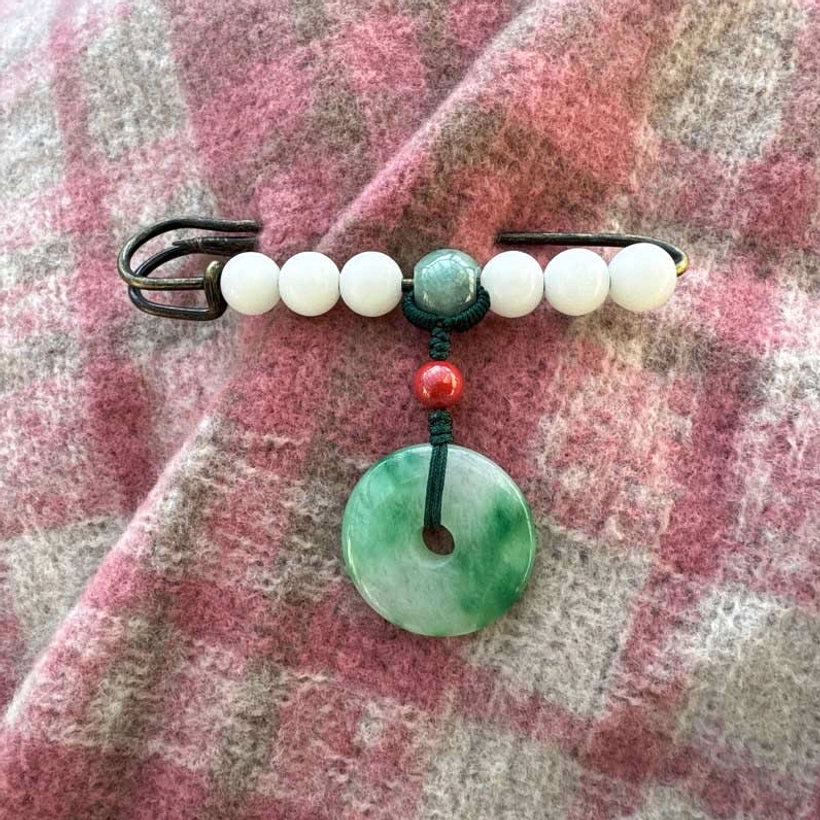Beaded safety brooch with white jade, green jade peace buckle and red accent on pink plaid fabric