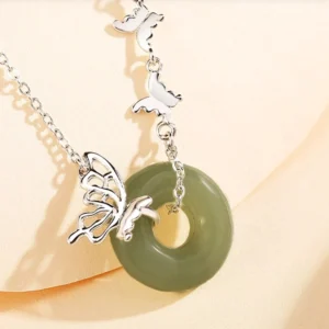 Close-up detail of jade peace buckle pendant with butterfly charm and silver chain showing craftsmanship