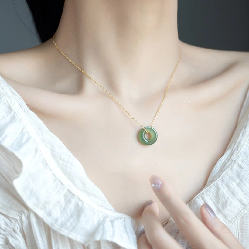 Detail shot of jade peace buckle pendant displaying smooth carved ring design with subtle natural jade variations on neutral background